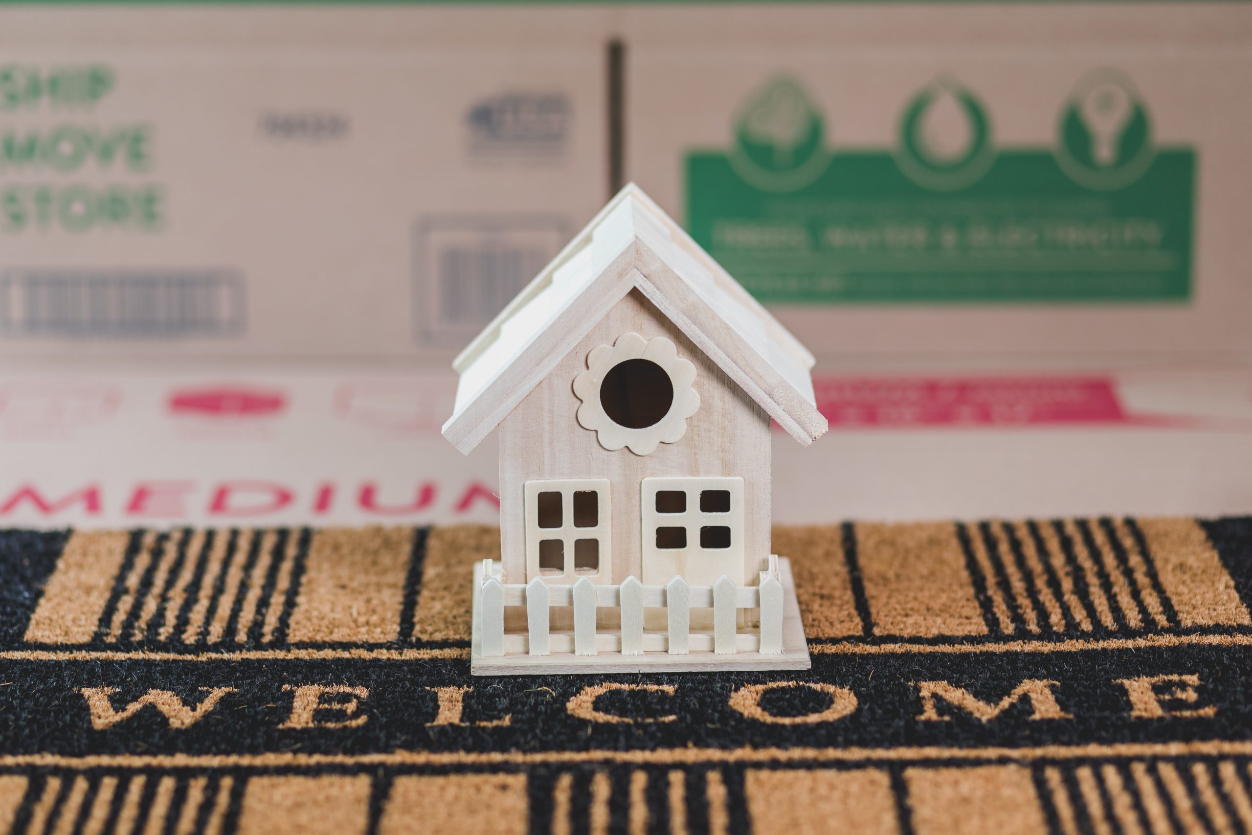 A model of a house positioned on a doormat.